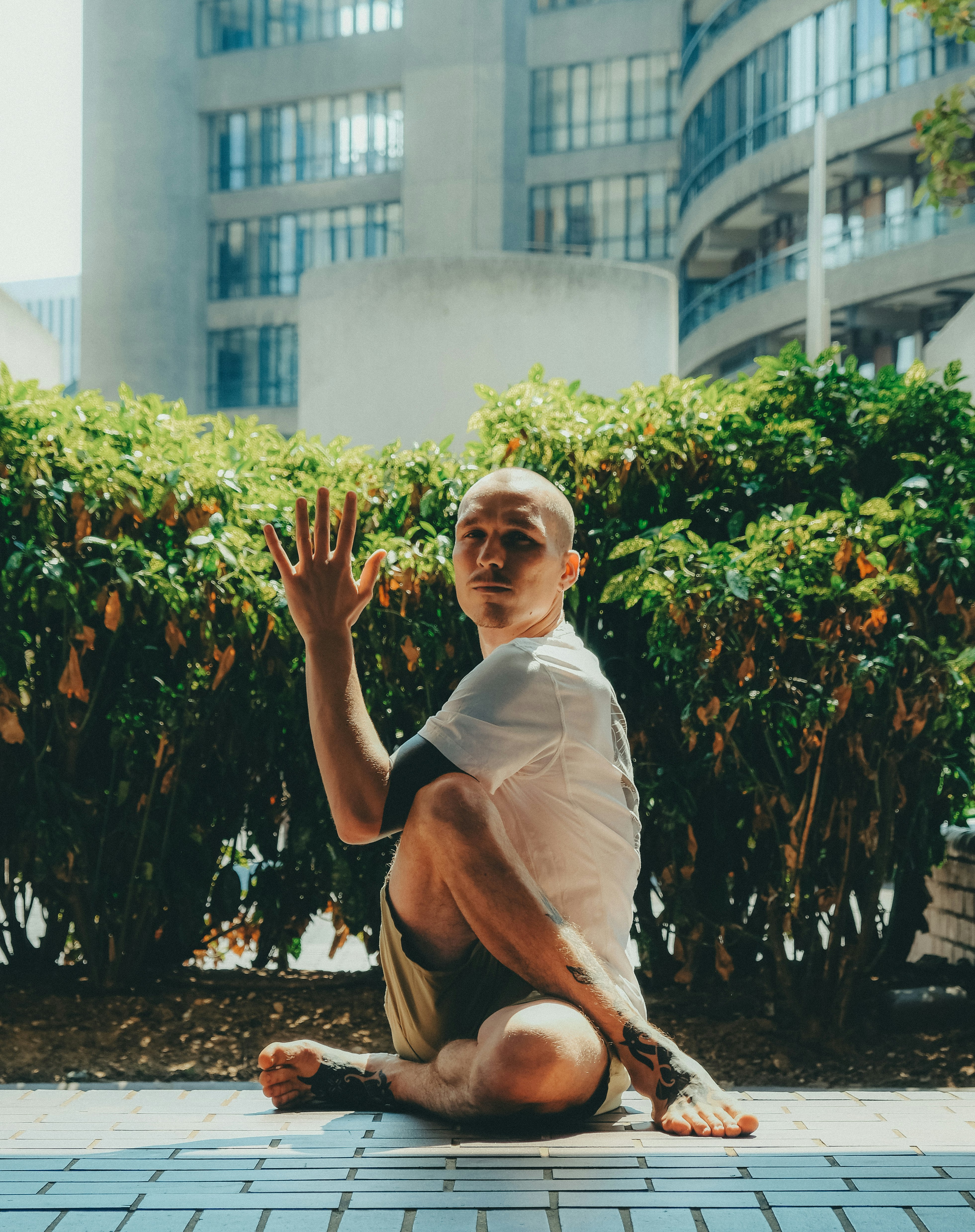 man in white crew neck t-shirt sitting on brown concrete floor during daytime